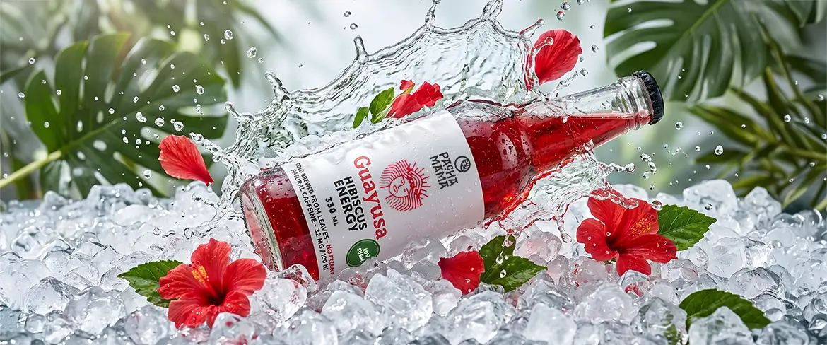 Sticlă de Guayusa Pachamama Cold Brew pe gheață pisată, cu flori de hibiscus.